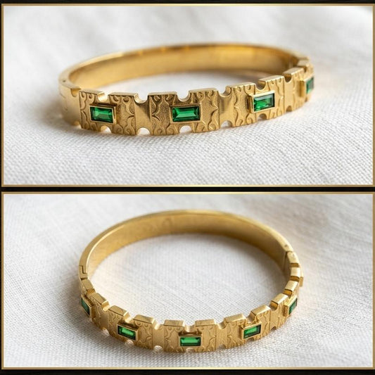 Gold bracelet with emerald stones on a white background