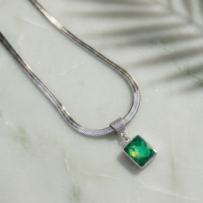 Silver necklace with a green pendant on a marble surface