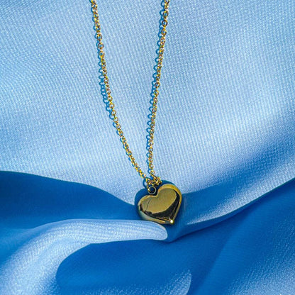 Gold heart-shaped pendant necklace on a blue fabric background