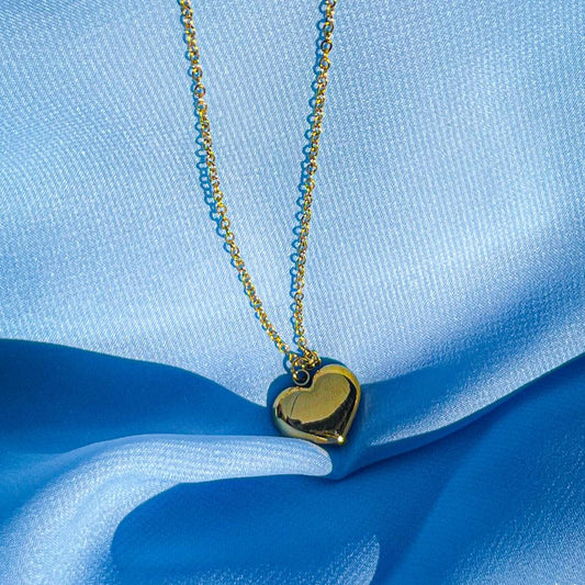 Gold heart-shaped pendant necklace on a blue fabric background