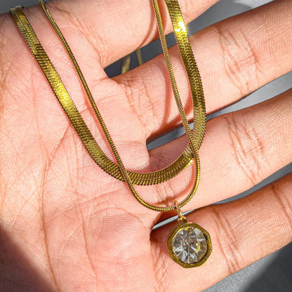 Gold necklace with a diamond pendant held in a hand