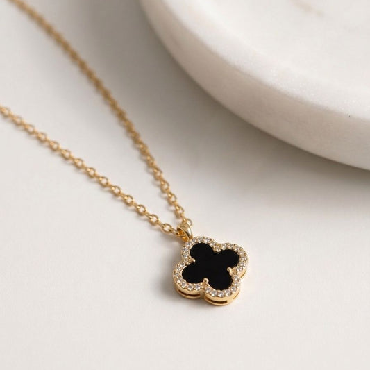 Gold necklace with a black pendant on a white background