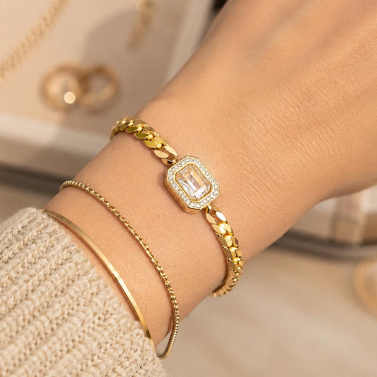 Gold bracelet with a diamond accent on a wrist, blurred background