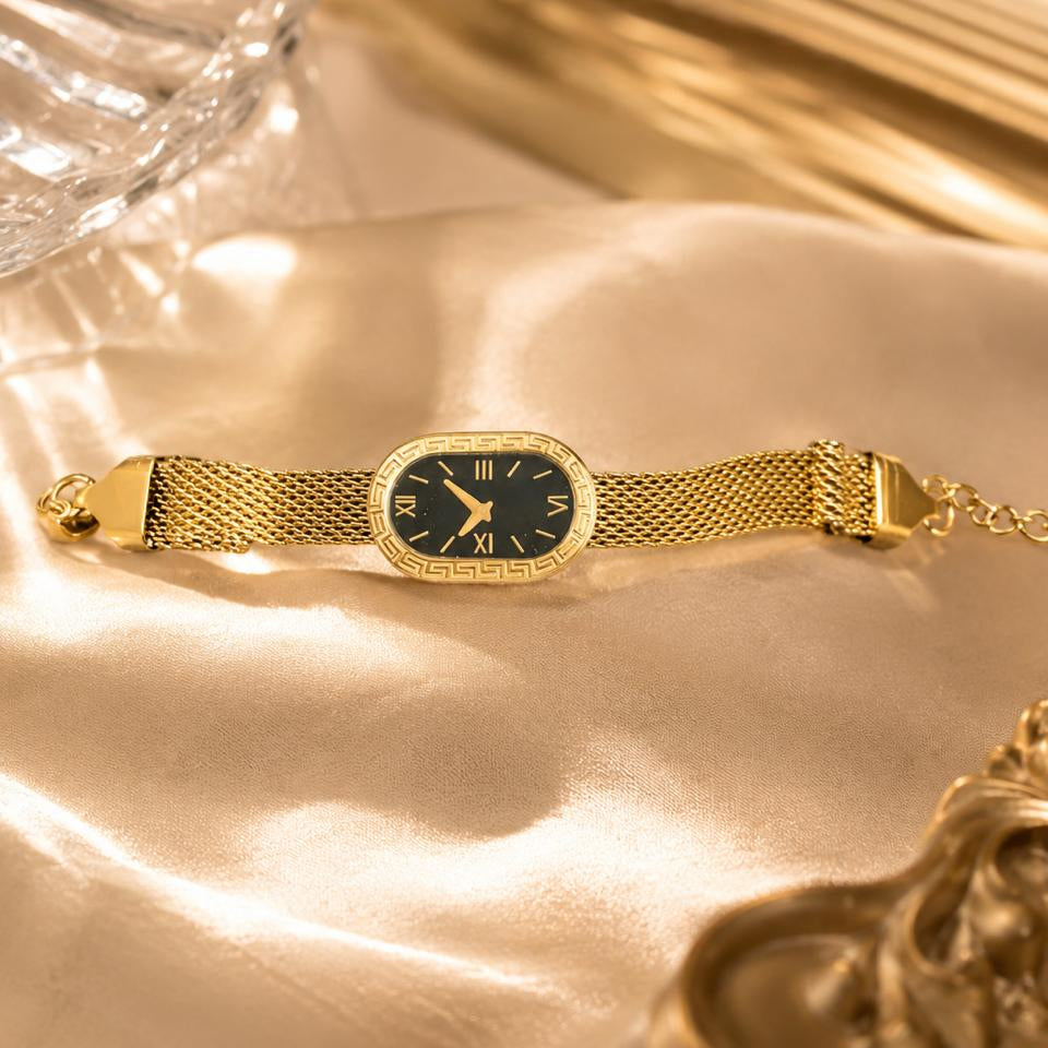 Gold bracelet with a black face on a gold surface