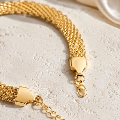 Gold bracelet with a clasp on a light stone surface