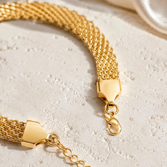 Gold bracelet with a clasp on a light stone surface