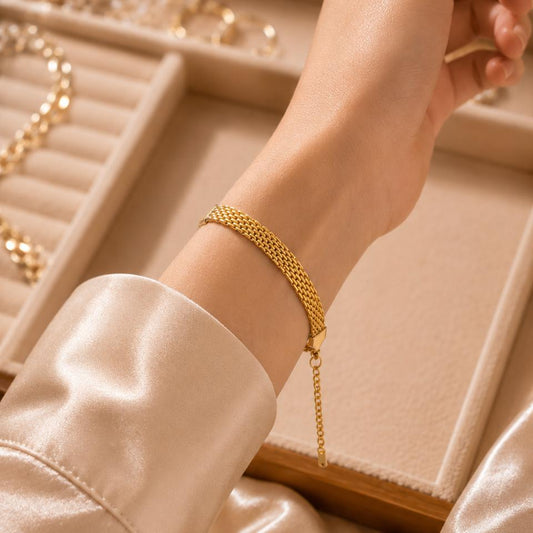 Gold bracelet on a wrist with a jewelry box in the background