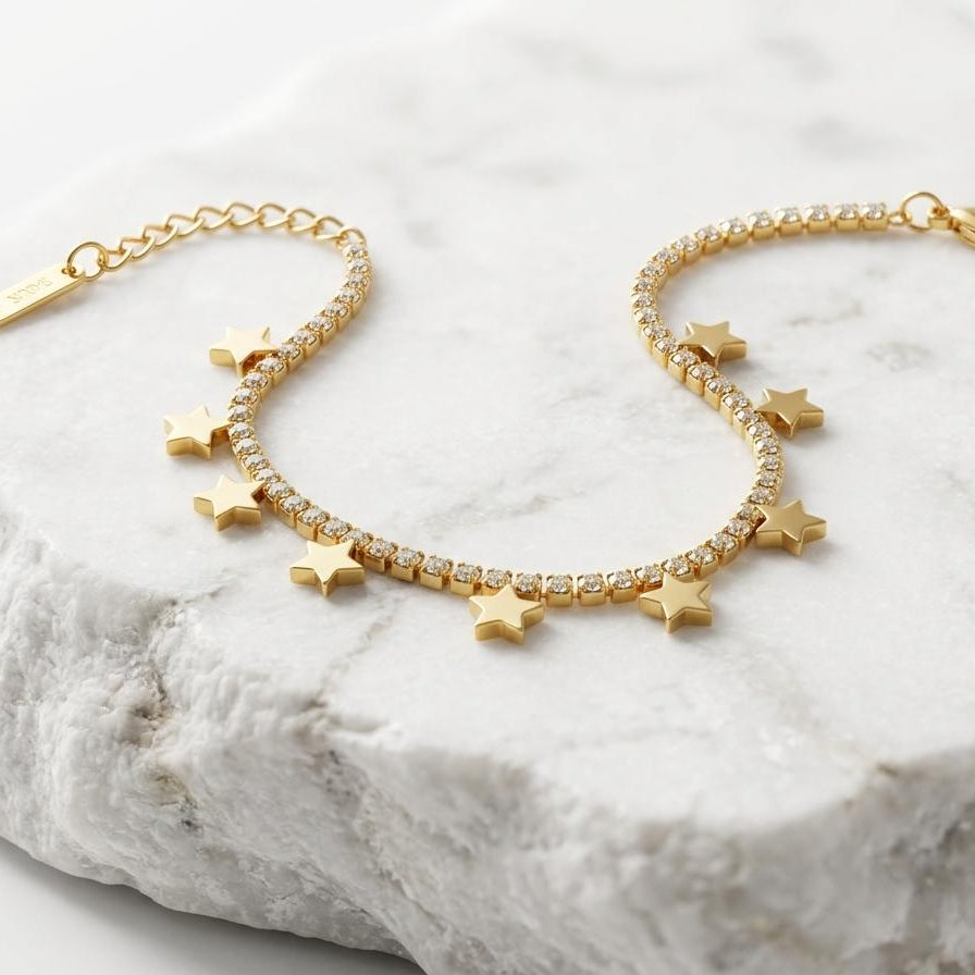 Gold bracelet with star charms on a marble surface