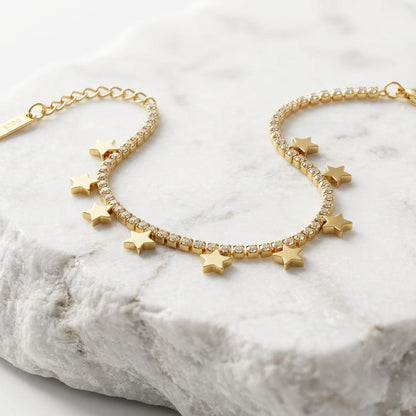 Gold bracelet with star charms on a marble surface