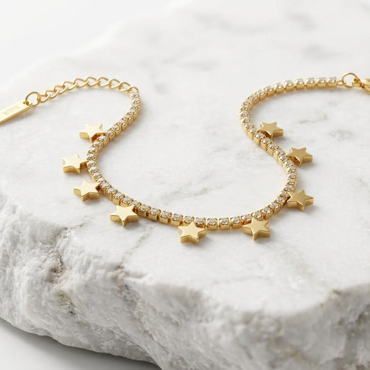 Gold bracelet with star charms on a marble surface